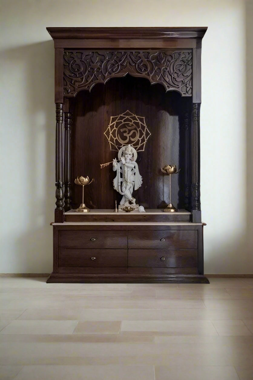 Modern pooja mandir against marble wall backdrop, adorned with a Krishna statue, lotus brass diyas, and detailed woodwork.