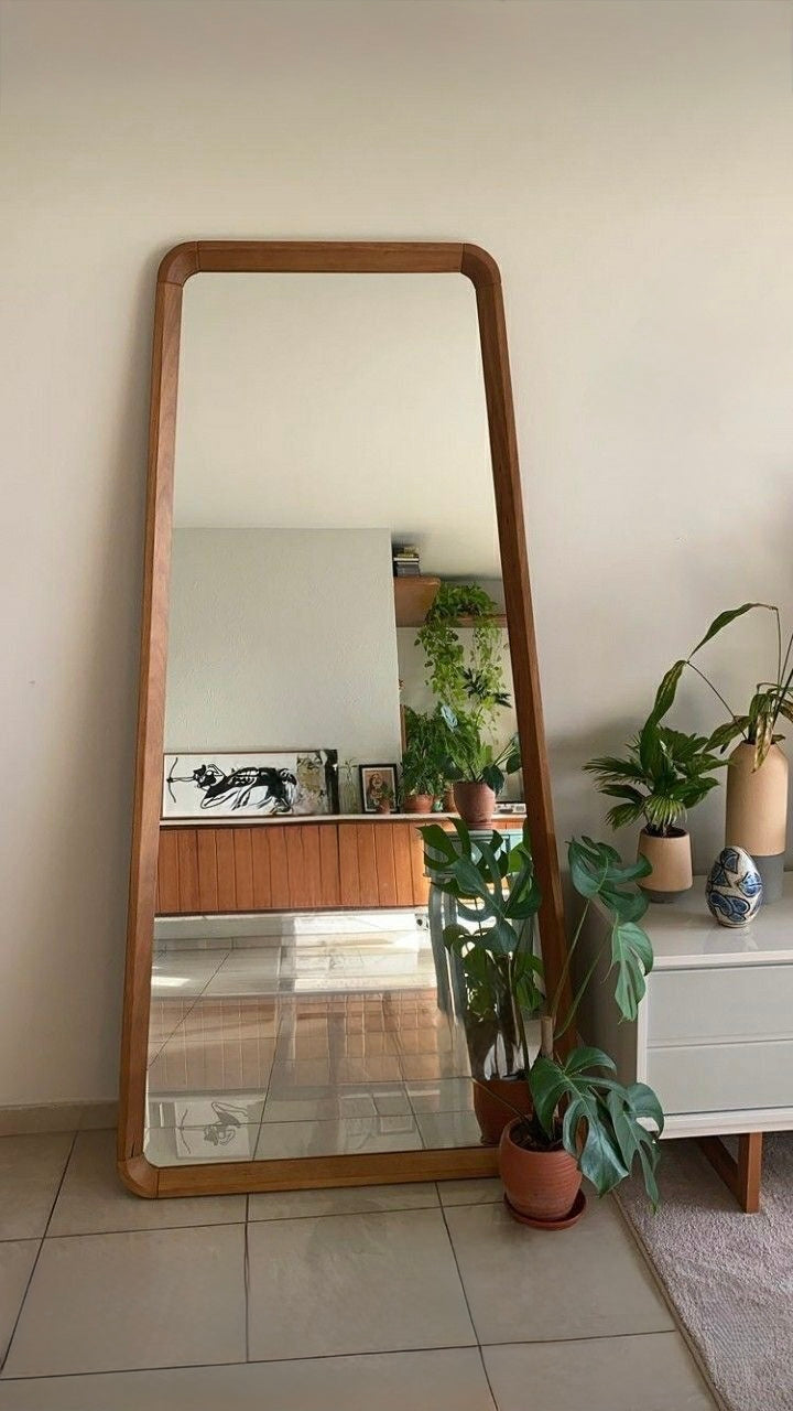 Contemporary full-length standing mirror with curved wooden edges, reflecting modern interior decor