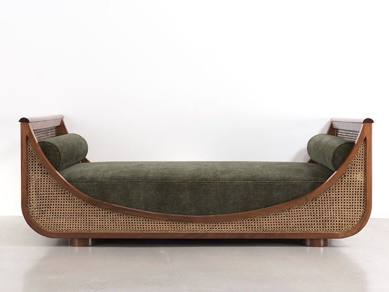 Elegant handcrafted teak wood sofa with cane weaving and olive green cushions, placed in a contemporary living room setting.