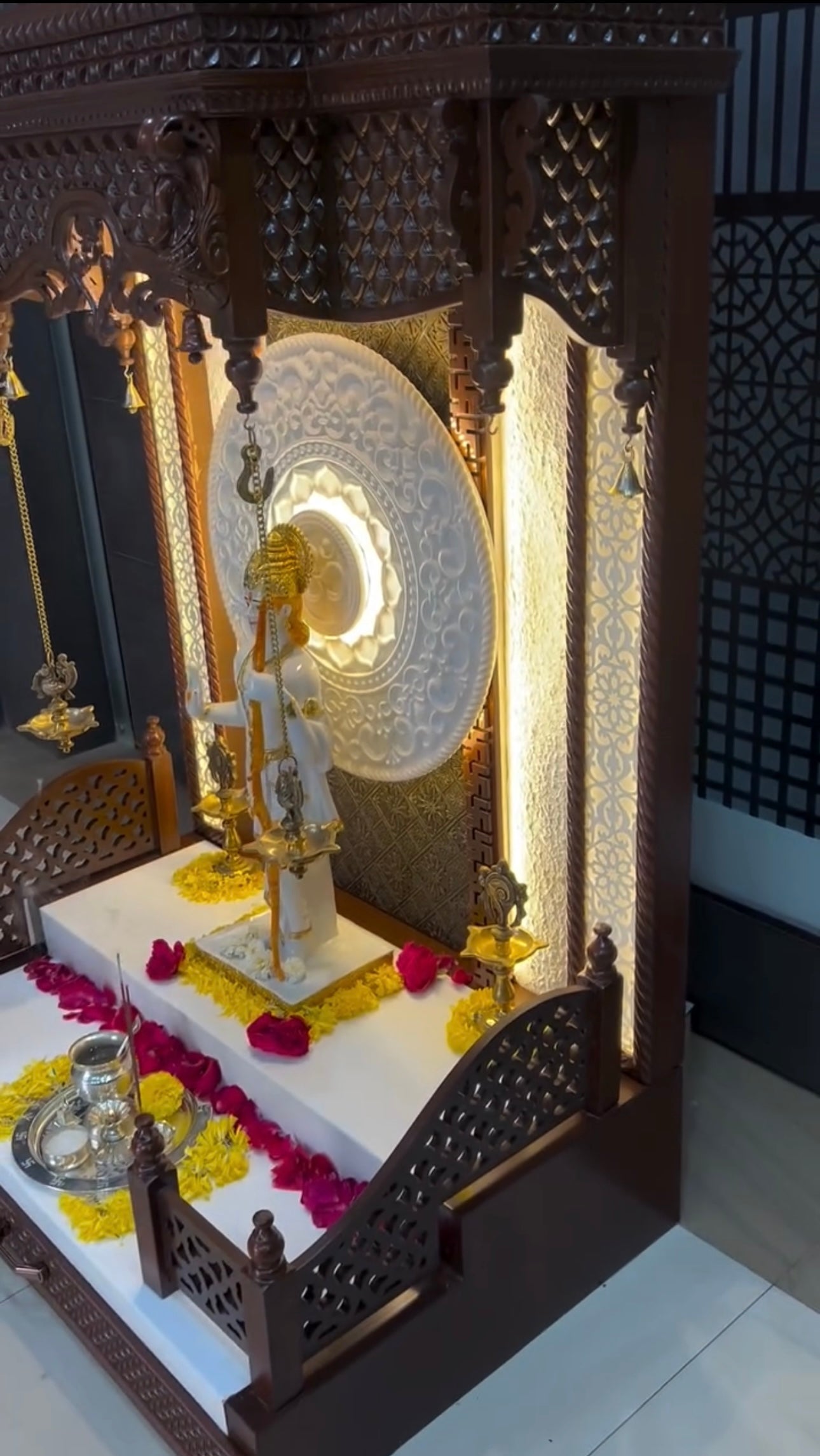 Intricately carved wooden mandir with backlit halo design and white marble platform for divine ambience.