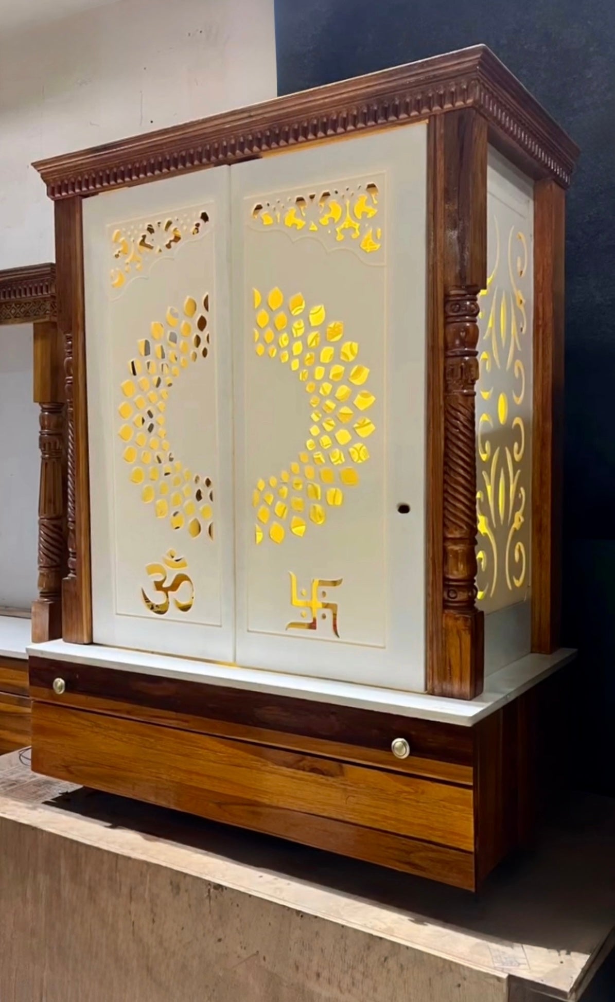 Elegant small wooden temple for home, made with polished teakwood and Corian stone, featuring sacred carvings and LED light highlights.