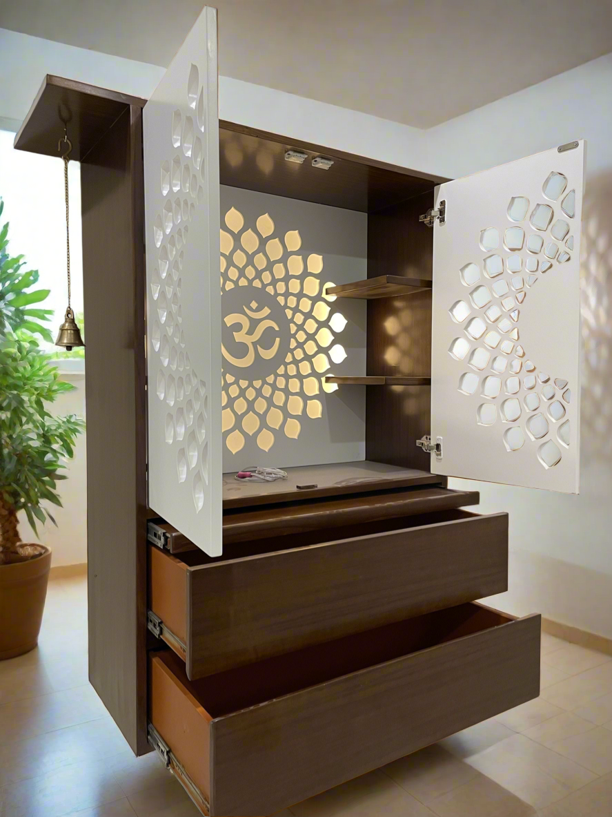 Elegant wooden home temple with white cutwork doors and an LED-lit "Om" symbol backdrop. Includes built-in shelves, pull-out drawers, and a brass bell, ideal for home or office prayer spaces.