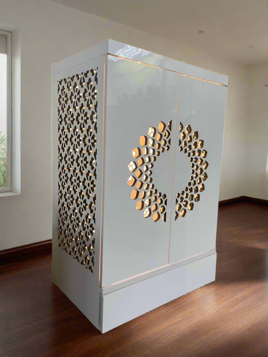 A compact yet elegant home mandir featuring a white polished finish, delicate lattice patterns on the sides, and soft golden lighting for a warm and peaceful ambiance.