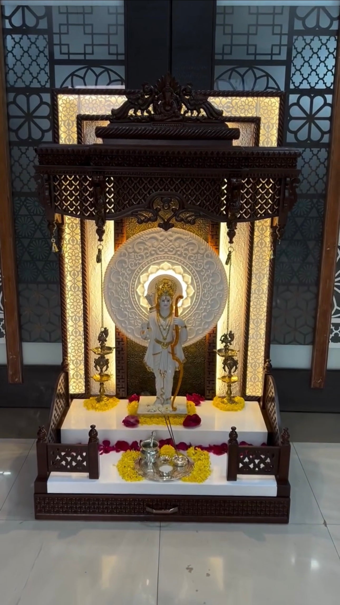 Designer wooden home temple with LED back panel, traditional carvings, and brass diya lamps – perfect for elegant pooja room setup.