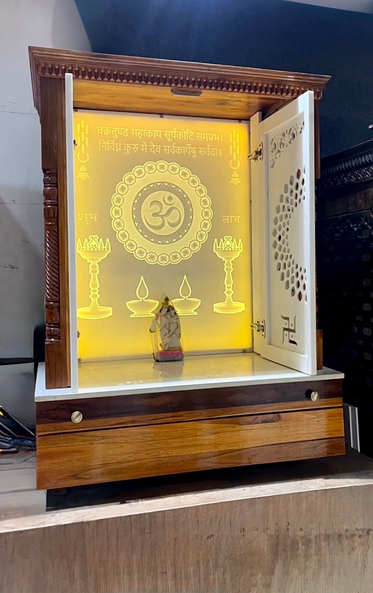 High-end wooden pooja mandir with laser-etched Om design, warm LED illumination, and modern wall-mount styling.