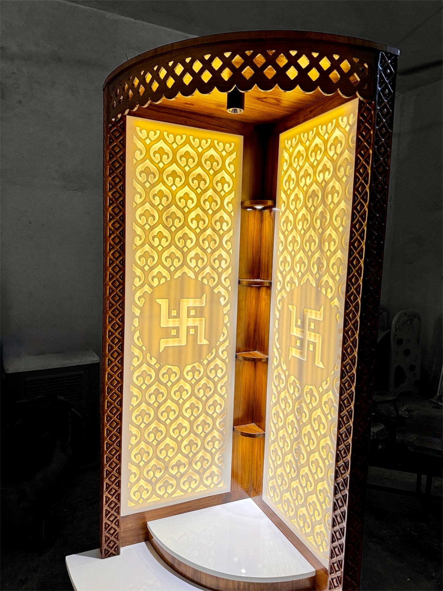 Teakwood corner mandir with Corian top and warm backlit ambiance