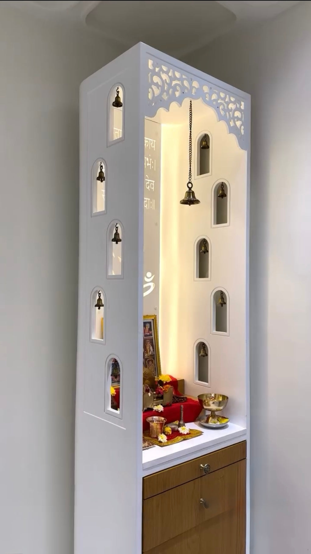 Handcrafted modern Pooja Mandir with storage space, designer cutwork panels, bells, LED backlight, and home temple setup.