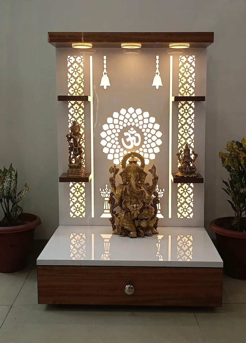 Modern wooden Pooja mandir with LED backlit Om symbol and intricate floral patterns, featuring brass idols of Lord Ganesha, Lakshmi, and Saraswati.