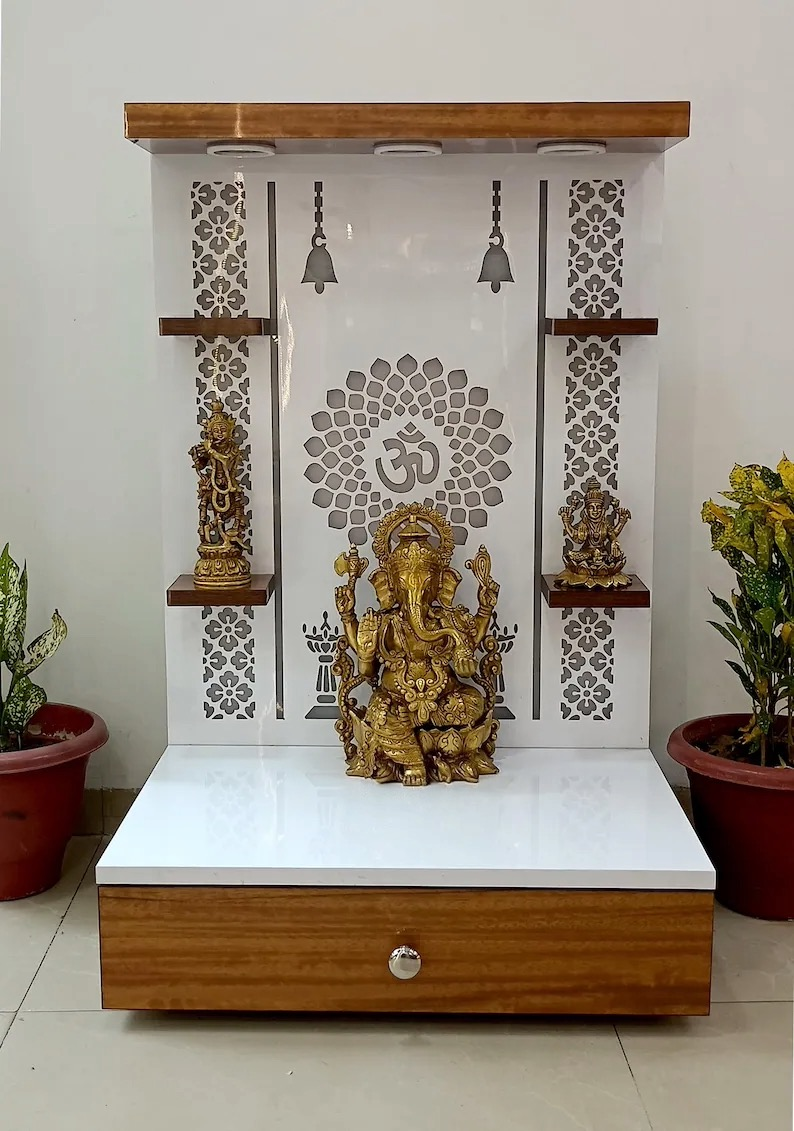 Elegant wooden Pooja mandir with white acrylic panel, floral laser-cut design, decorative shelves, and Ganesh idol for home temple décor