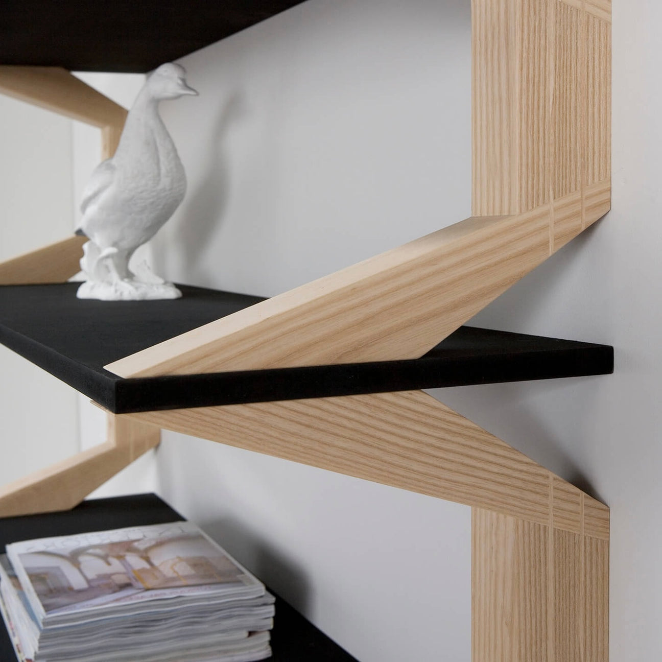 A contemporary floating shelf with an artistic wooden frame and sleek black surfaces, perfect for stylish home organization.