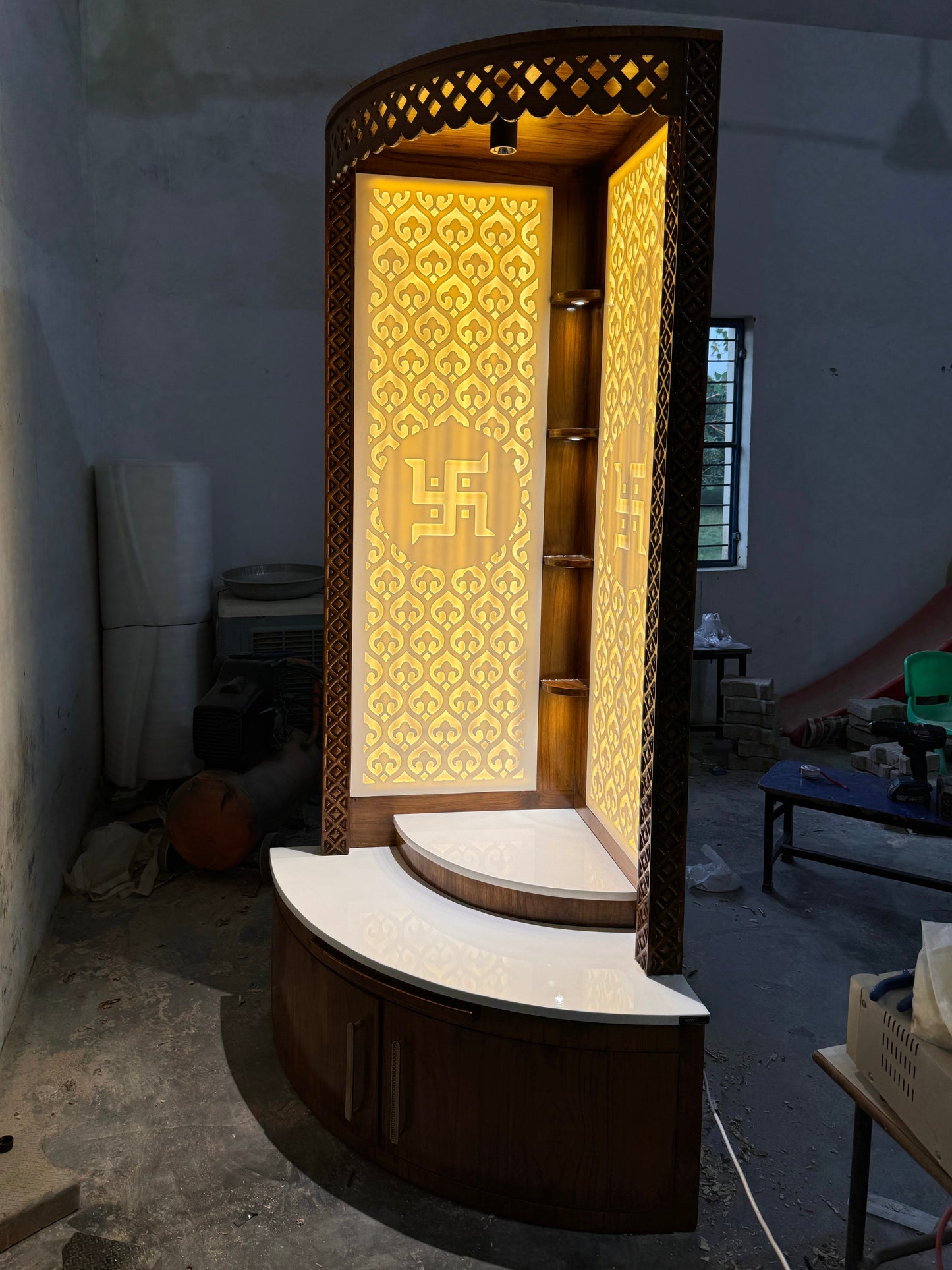 Modern wooden temple with glowing 3D Swastik cutout and white Corian base
