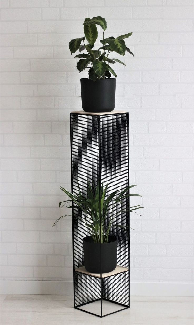 Modern vertical plant holder with minimalist mesh metal design, styled with black planters and indoor plants