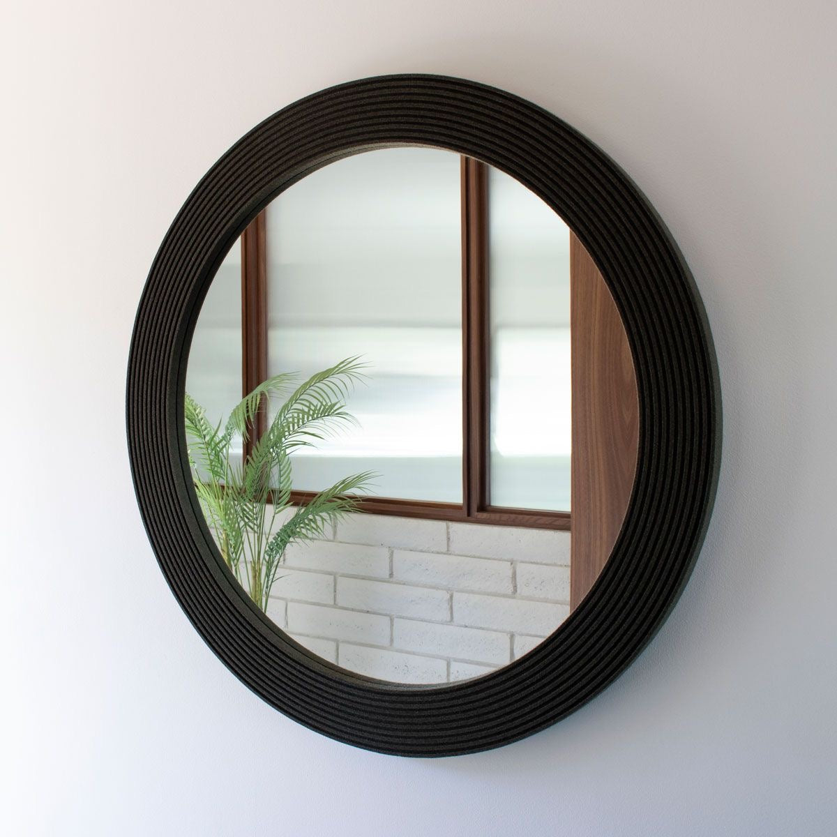Elegant black round wall mirror with textured frame, adding a modern touch to home interior decor