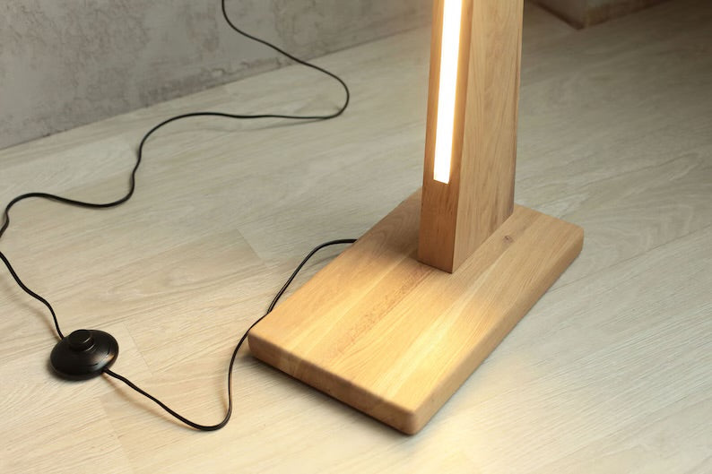 Solid wood base of curved LED floor lamp with visible foot on/off switch and power cord connection.