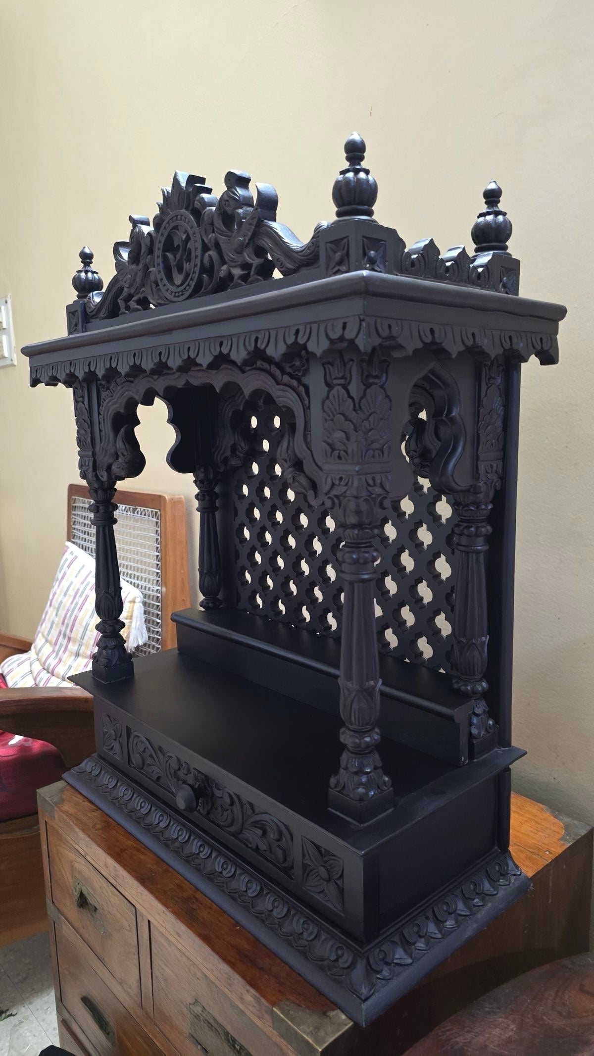 Traditional solid wood home temple with carved pillars and jaali back panel