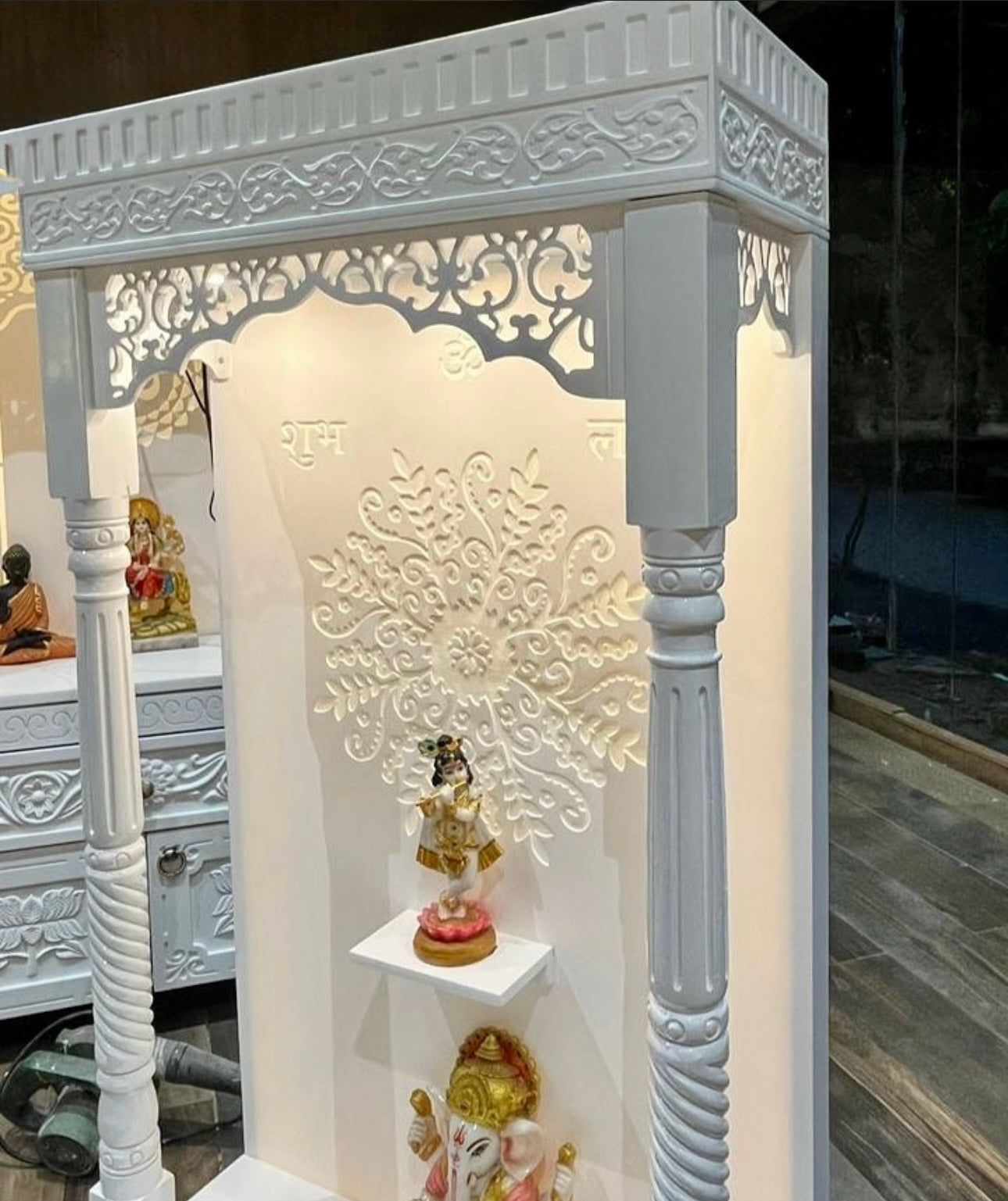 Designer white wooden mandir with LED lighting, Krishna and Ganesha idol setup.