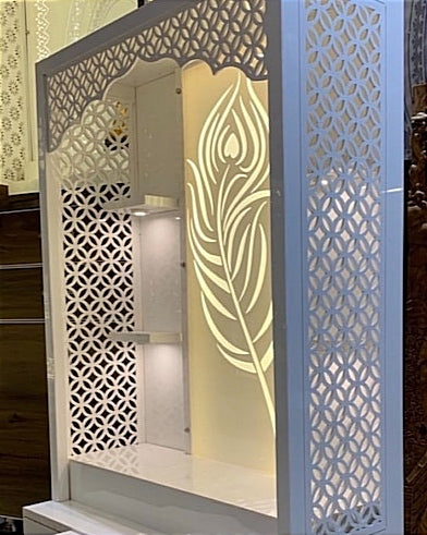 A stunning pooja mandir featuring a glowing peacock feather design, side lattice panels, and built-in shelves for an elegant spiritual corner.
