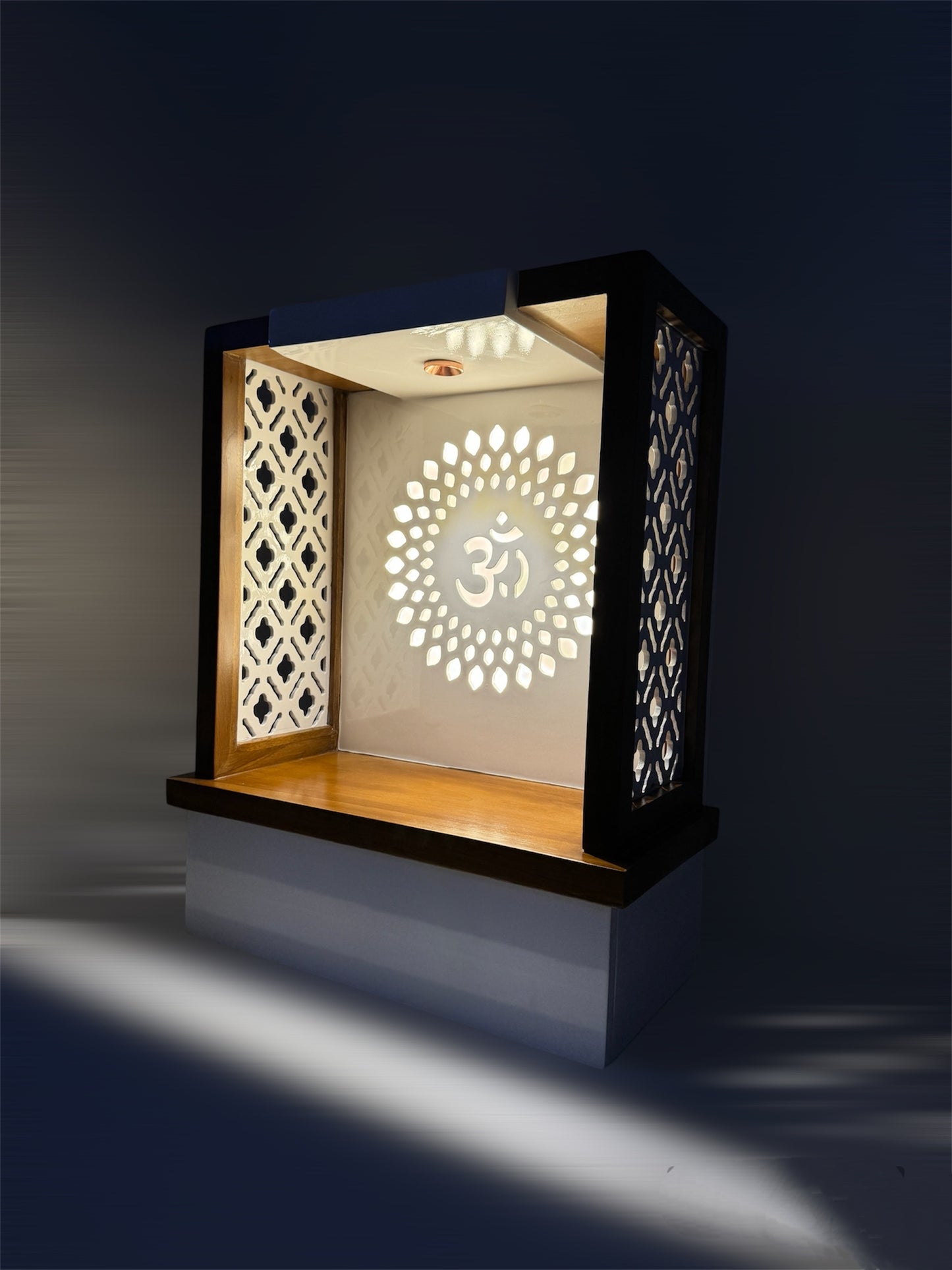 Minimalist temple design featuring intricate jali side panels, backlit Om symbol, and spacious drawer for spiritual essentials.