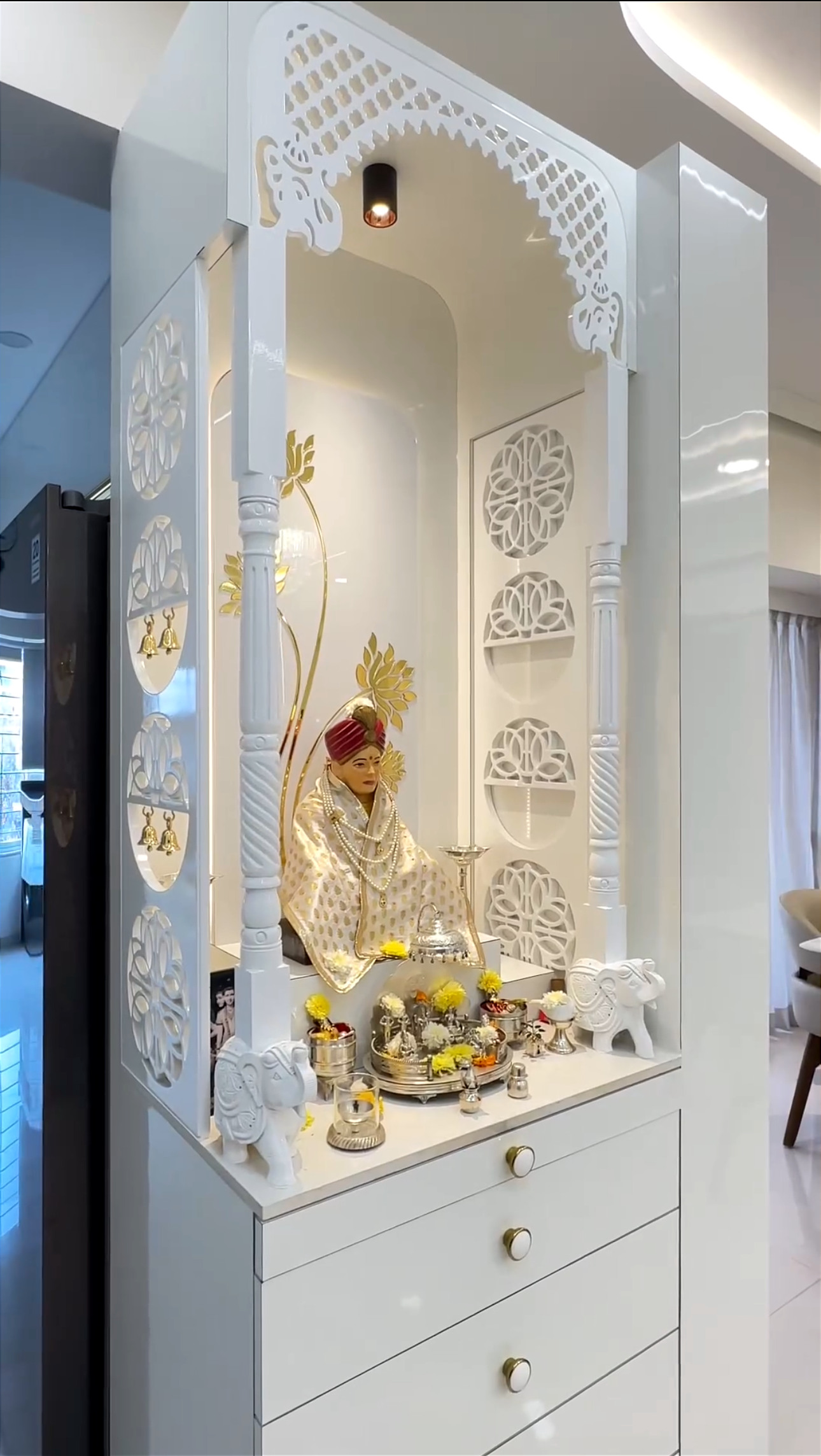 Beautiful white Pooja temple with side panel cutwork design, gold floral backdrop, and detailed craftsmanship – perfect for a serene and modern home mandir.