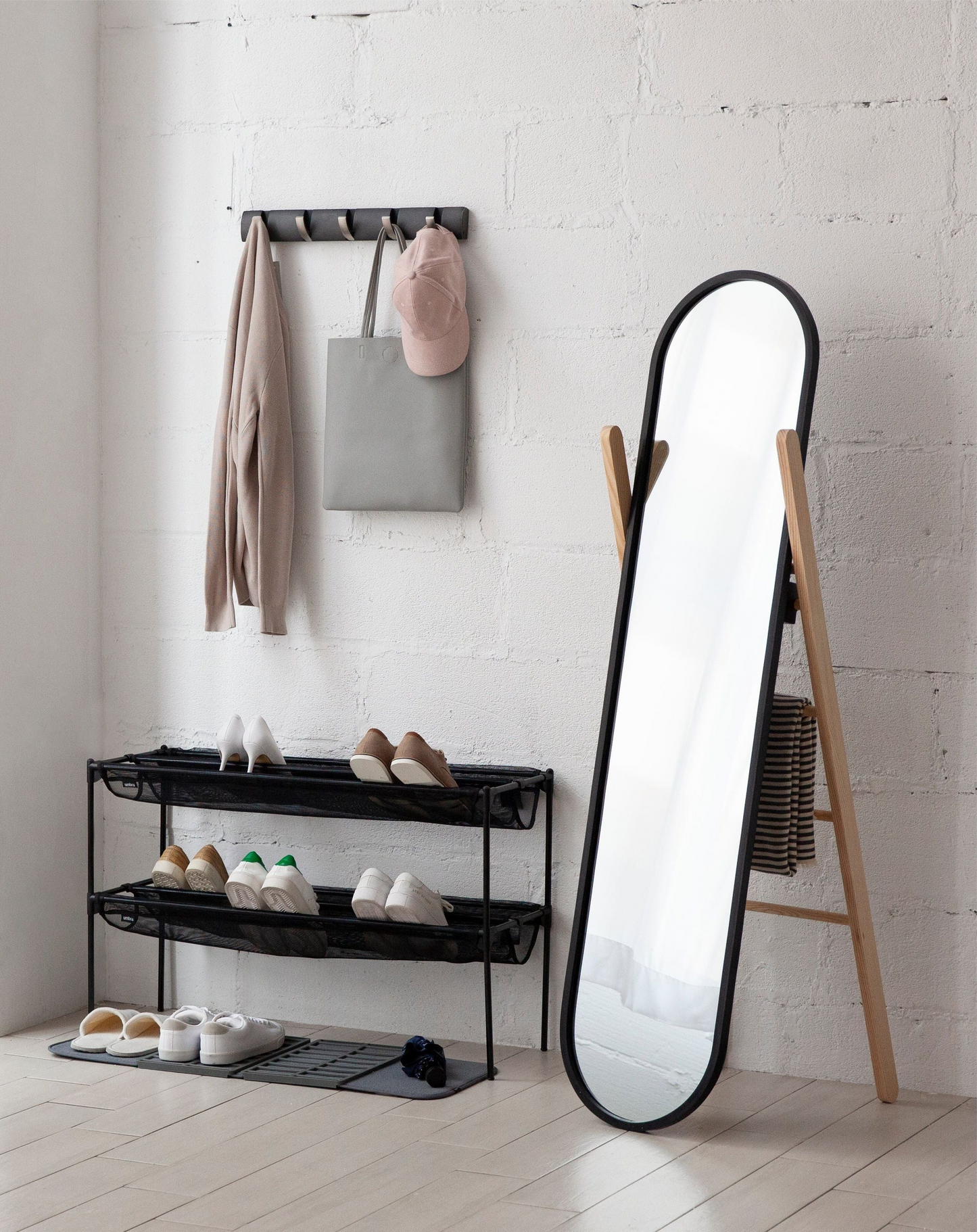 Freestanding oval dressing mirror with natural wood stand in minimalist entryway