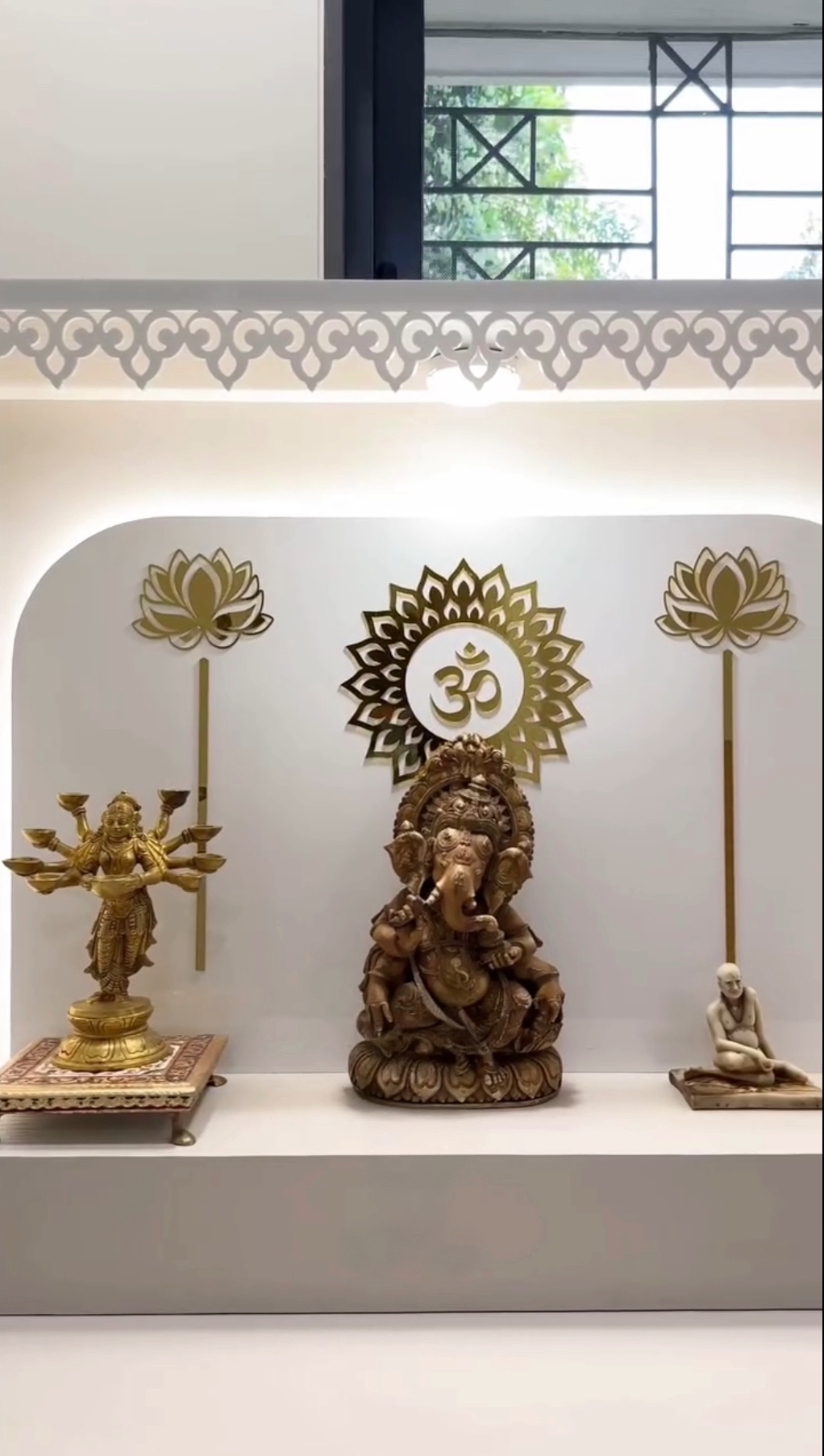 Contemporary home temple with curved arch, golden Om symbol, and lotus wall accents.