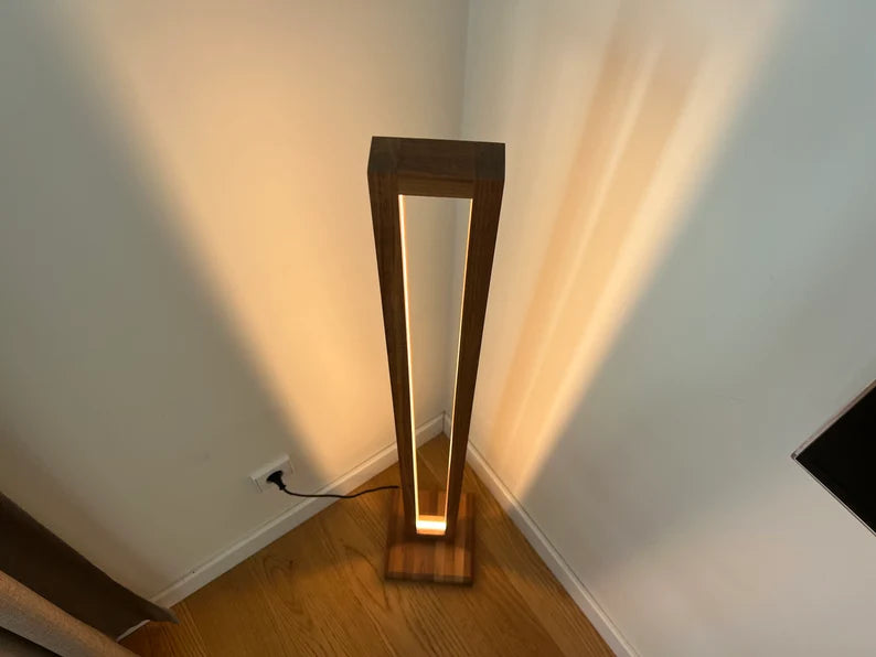 Wooden floor lamp casting a warm glow on a white wall.