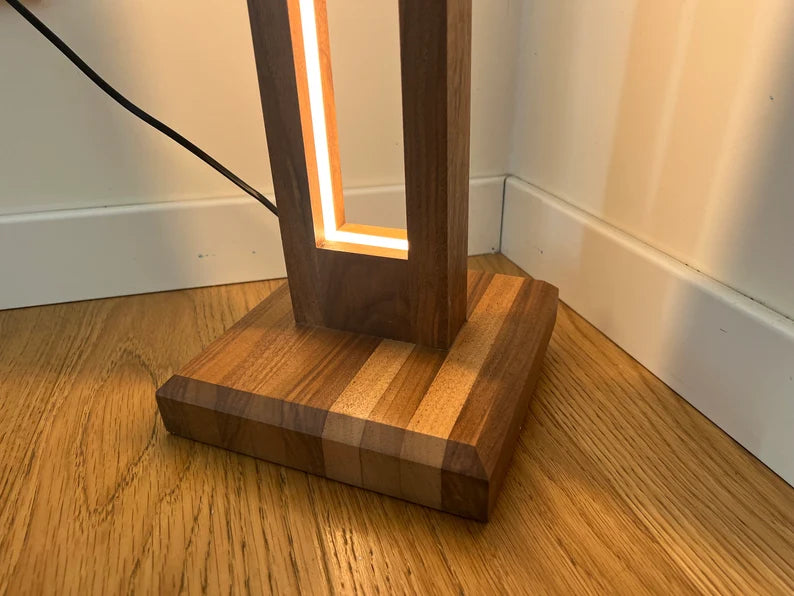 Wooden lamp with a glowing base on a wooden floor