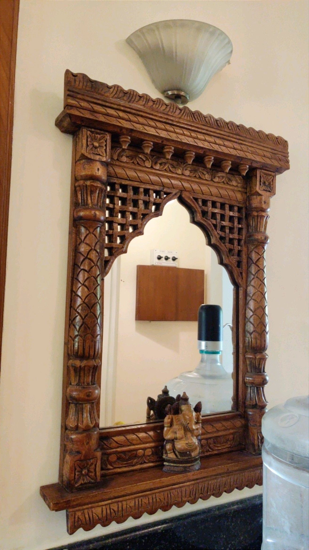 Ethnic carved wooden Jharokha mirror frame with floral motifs and Lord Ganesh statue – handcrafted Indian wall art.