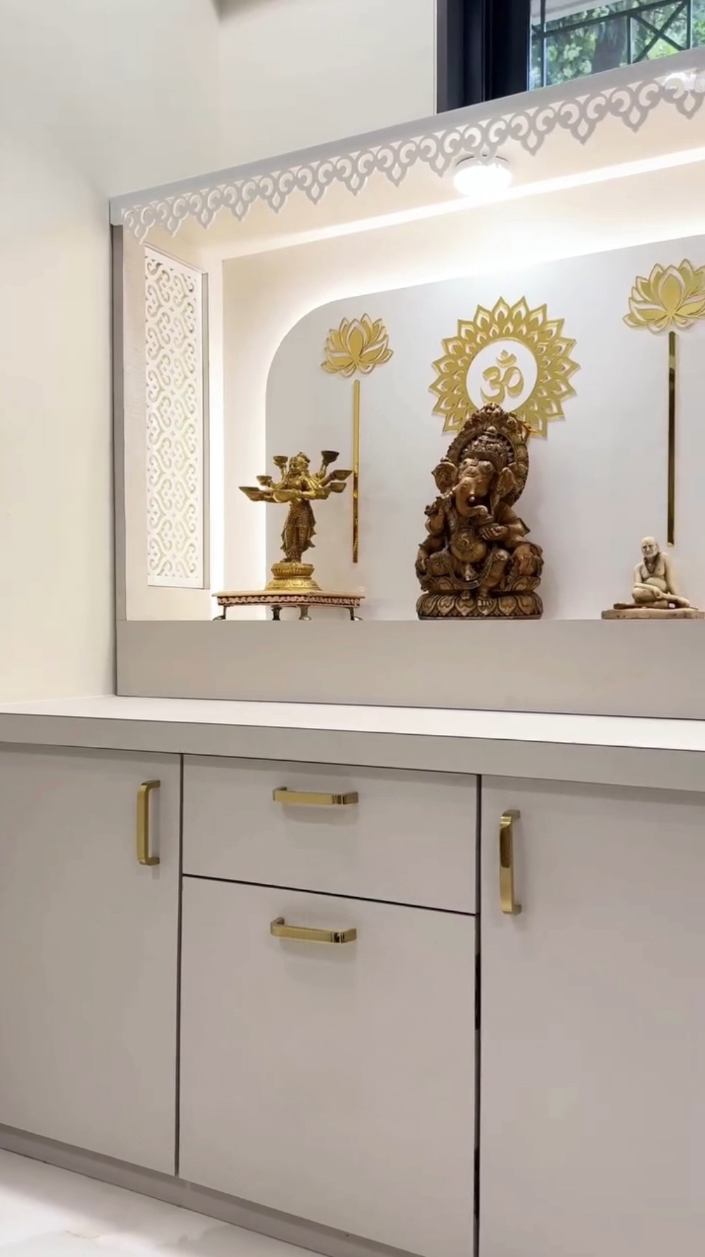 Stylish white mandir with intricate CNC jaali, storage drawers, and decorative golden elements for home.