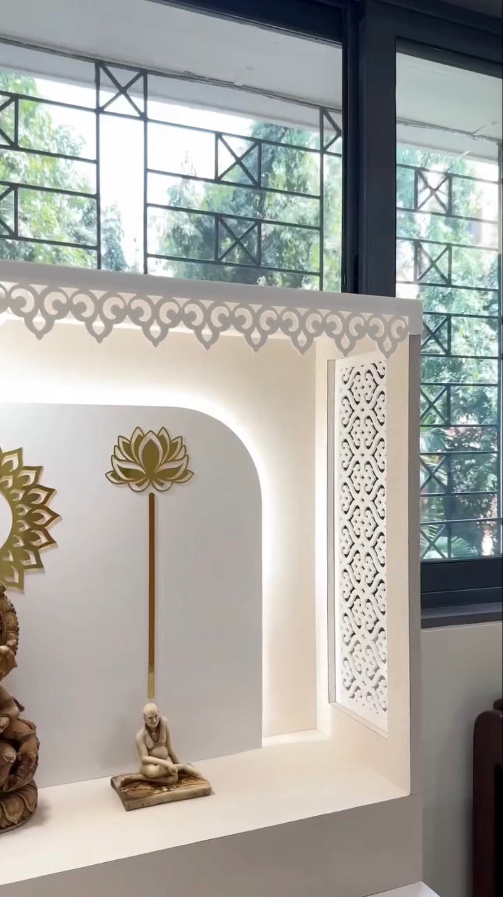 Designer pooja unit with Ganesh backdrop and warm LED lighting.