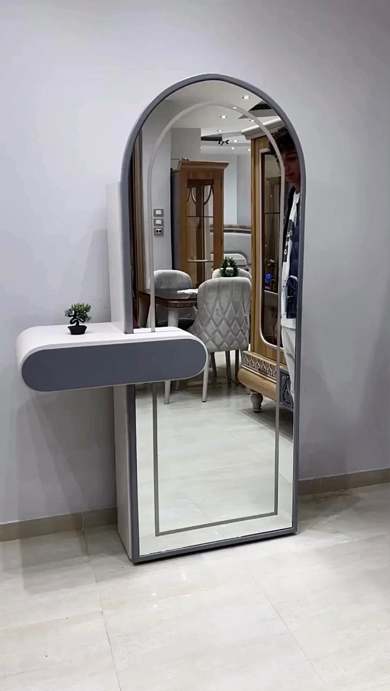 Modern arched LED mirror vanity with floating shelf in bedroom interior