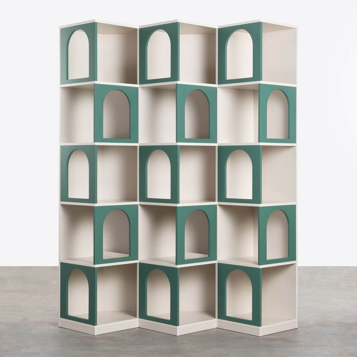 Modern modular bookshelf with green arch-shaped cutouts and zigzag design, standing on a concrete floor against a white background.