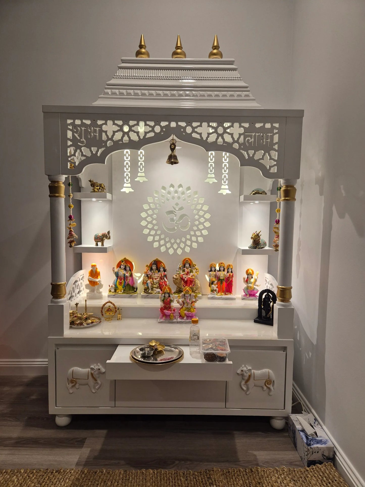 Premium white pooja mandir for home with ornate design, backlit OM symbol, and side shelves for diya and decor