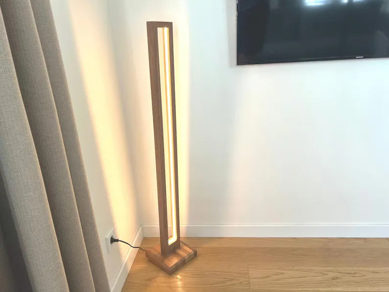 Floor lamp with a wooden base and LED strip light in a room with curtains and a TV.
