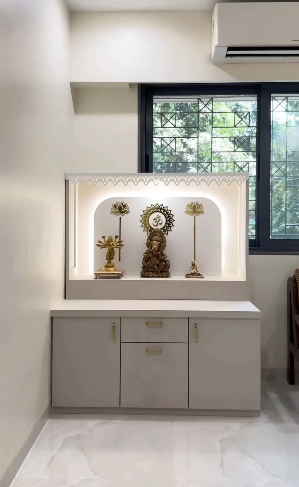 Modern white pooja mandir with LED backlighting, golden Om motif, lotus wall decor, and storage cabinets.