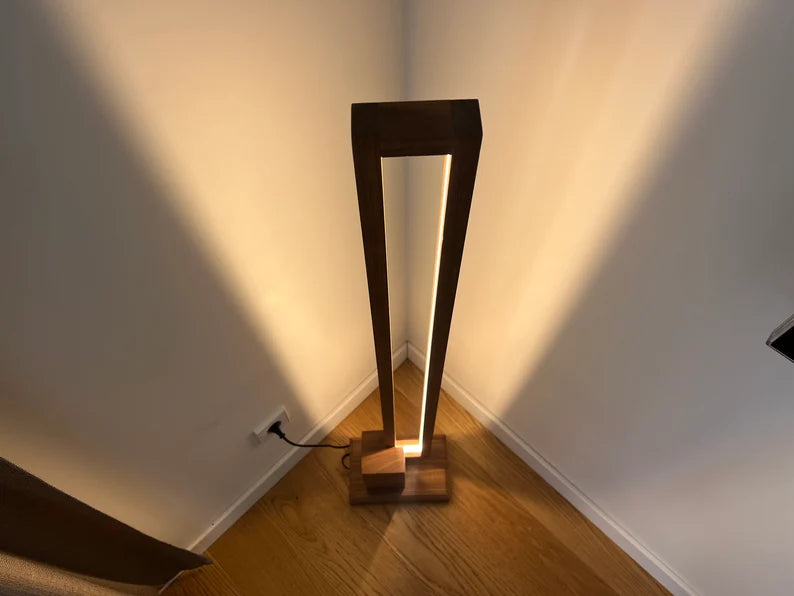 Modern floor lamp casting light on a wall in a room.