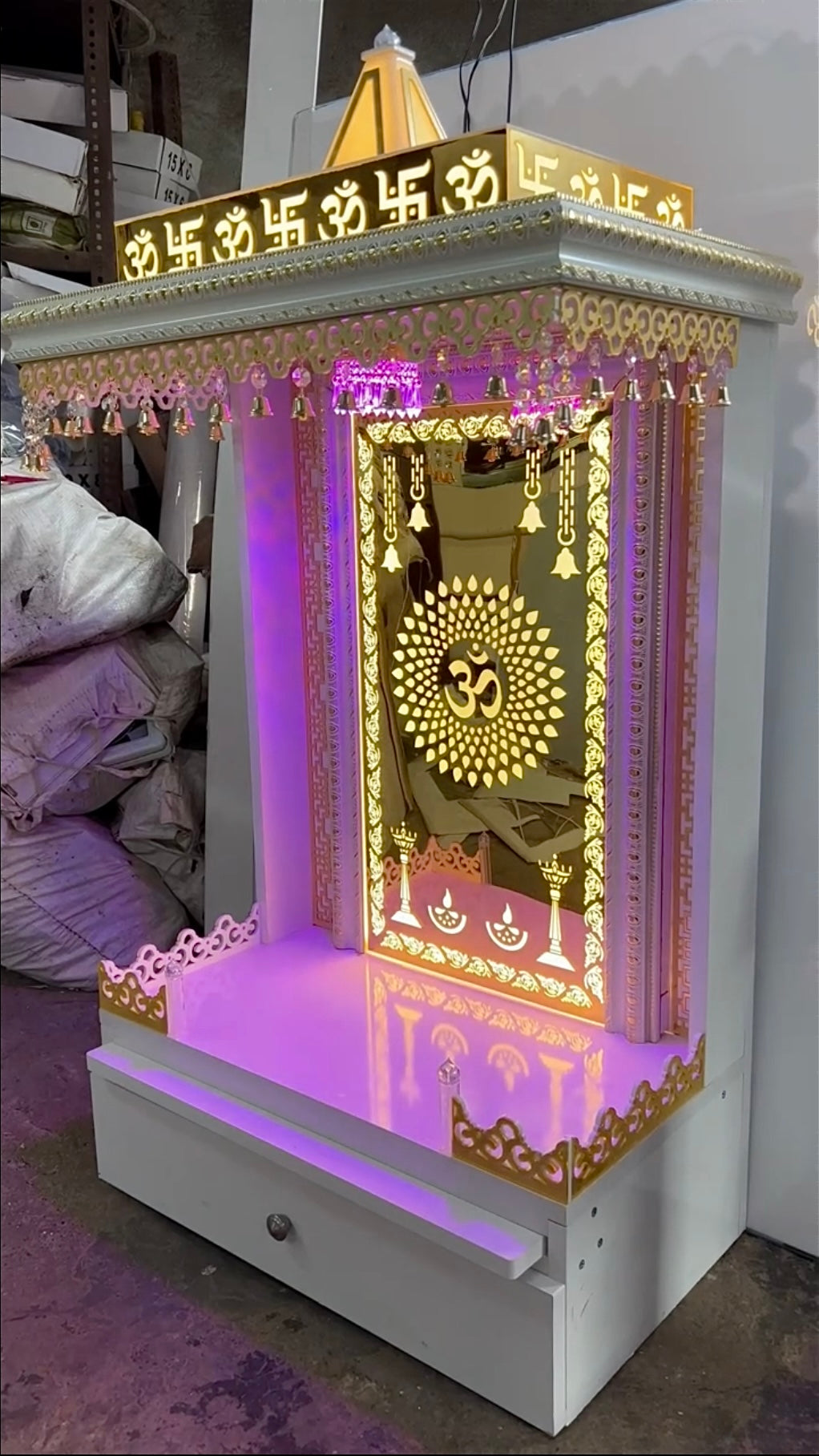 Elegant white and gold handcrafted wooden Pooja Mandir with golden illuminated Om and decorative bells