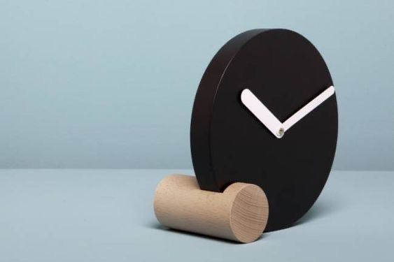 Minimalist Tabletop Clock Showcases A Sleek Black Circular Face - Resting On A Cylindrical Natural Wood Base