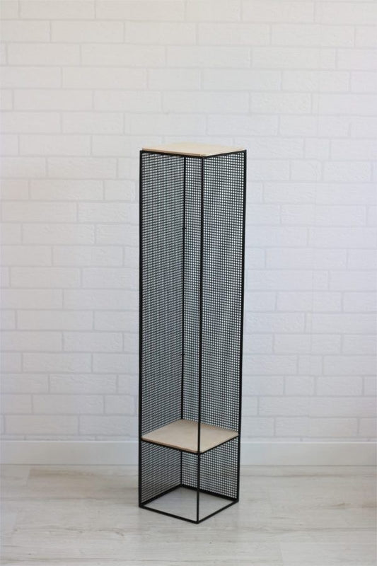 Tall black metal indoor plant stand with two-tier design holding potted green plants against white brick wall