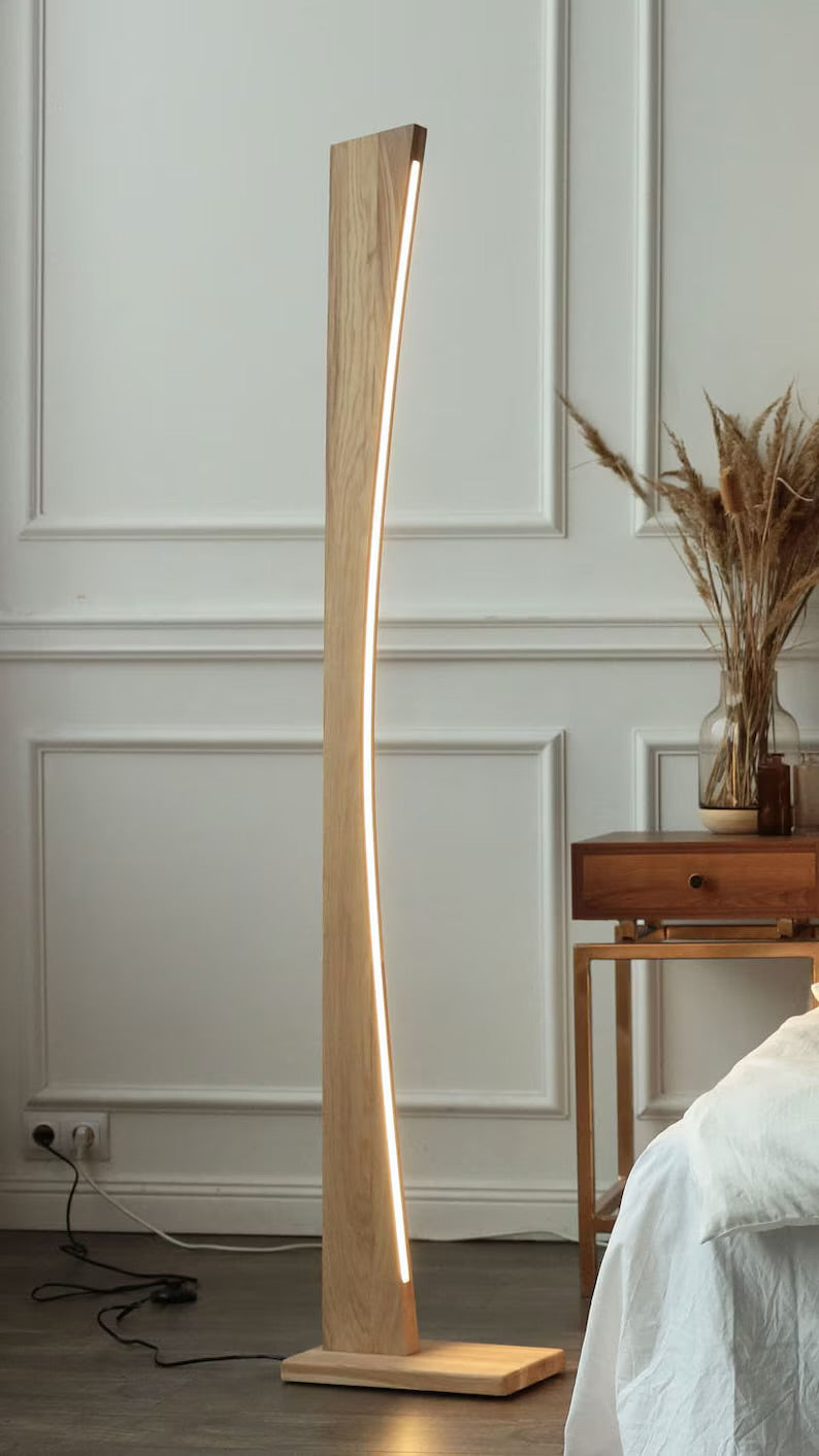 Elegant wooden floor lamp with curved LED strip lighting, blending into a cozy bedroom with natural decor.