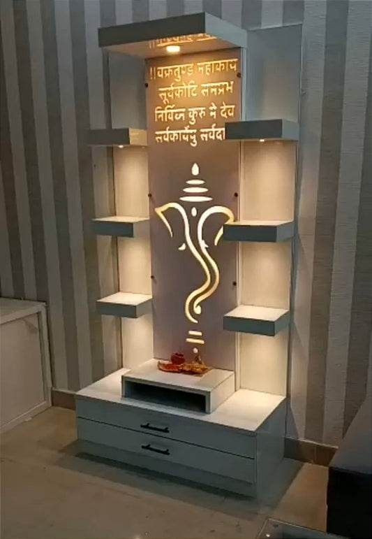 A beautifully crafted white wooden pooja unit featuring a glowing Ganesha cutout with soft LED backlighting, golden Sanskrit inscriptions, and decorative shelves, perfect for contemporary home interiors.
