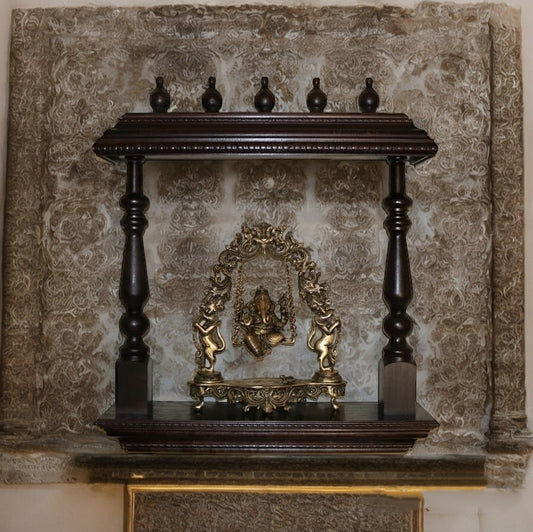 Handcrafted wooden mandir shelf with hanging Ganesha idol in brass, designed for aesthetic and devotional appeal in home interiors.