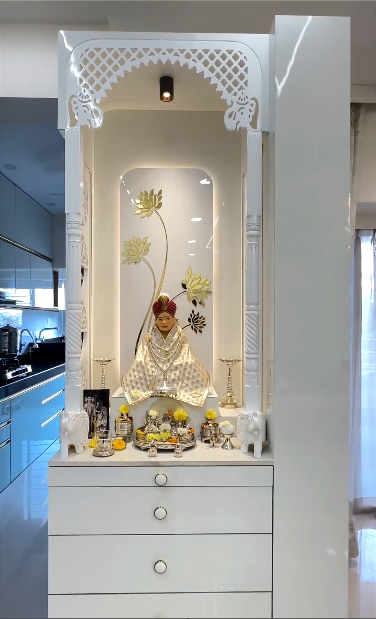 Elegant white wooden Pooja temple with intricate carved detailing, featuring gold floral accents and traditional decorative elements, ideal for a modern home mandir.