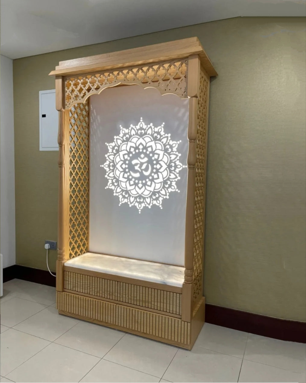 Beautiful hand-carved wooden Pooja mandir with backlit Om mandala and marble seat, ideal for creating a sacred prayer area.