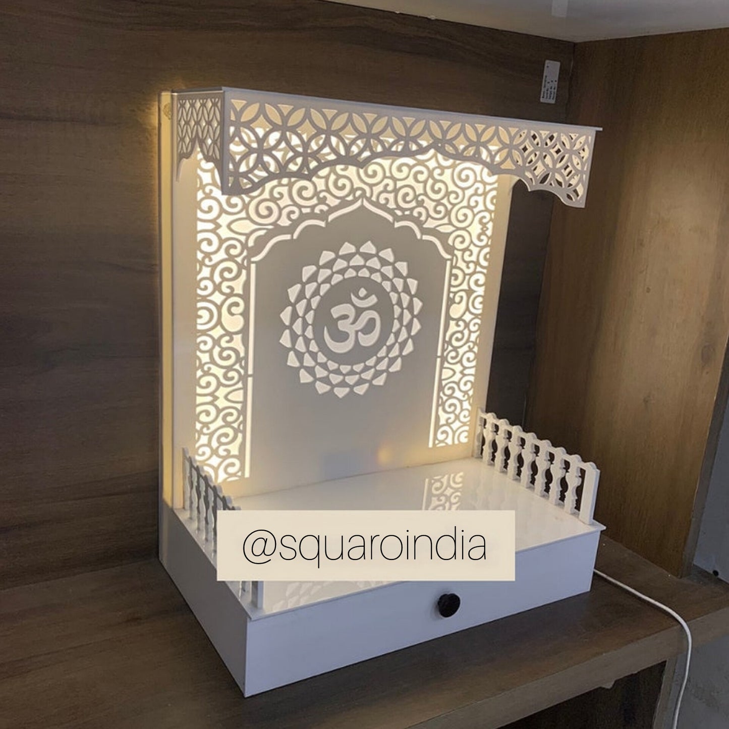 Space-saving Corian wooden temple with a beautifully carved Om symbol, intricate Jali work, and soft LED lighting, designed for modern home interiors.